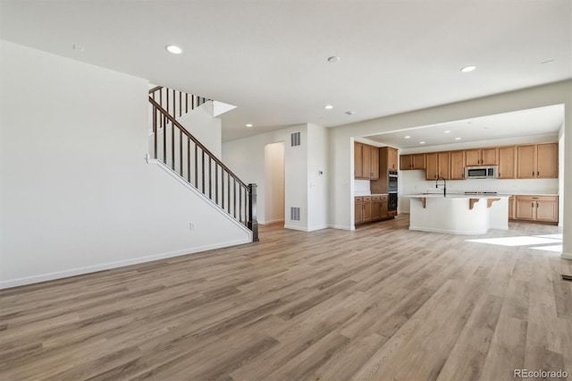 unfurnished living room with sink and light hardwood / wood-style flooring