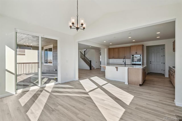 kitchen with a kitchen island, light hardwood / wood-style floors, oven, hanging light fixtures, and lofted ceiling