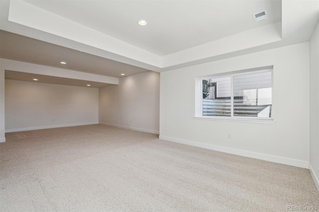 carpeted empty room with a raised ceiling