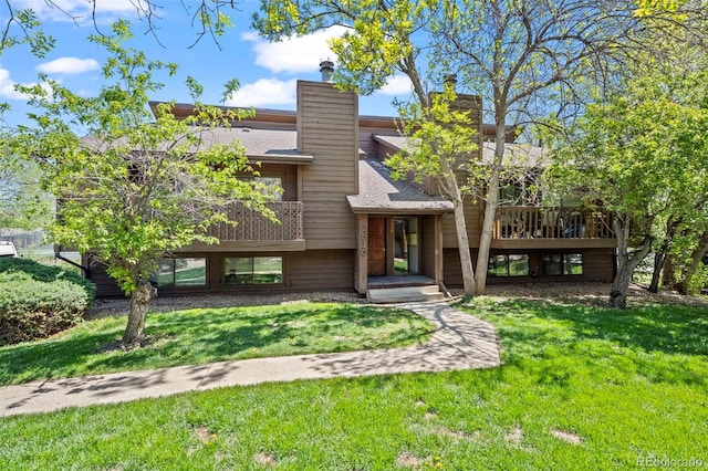 view of front of property featuring a front lawn, a chimney, and a deck
