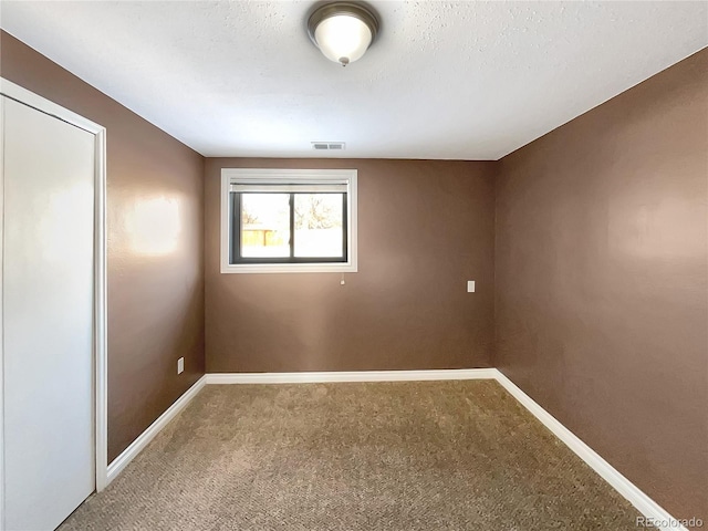 unfurnished room with carpet flooring and a textured ceiling