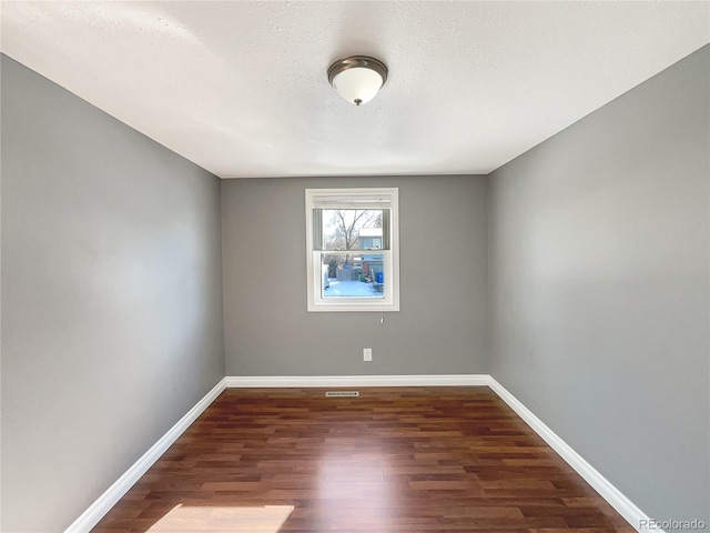 empty room with dark hardwood / wood-style floors and a textured ceiling