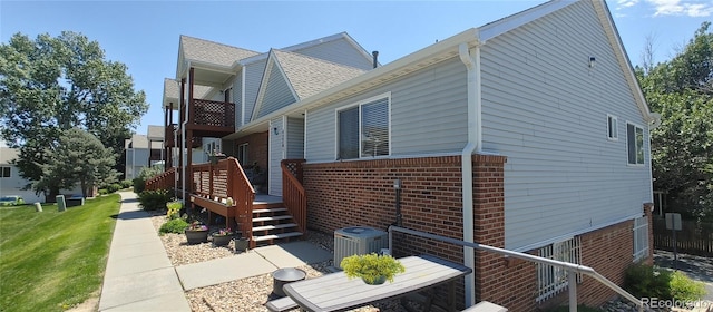 4220 E 119th Pl Unit A, Thornton, CO 80233 - view of side of home featuring brick siding, a deck, and a yard