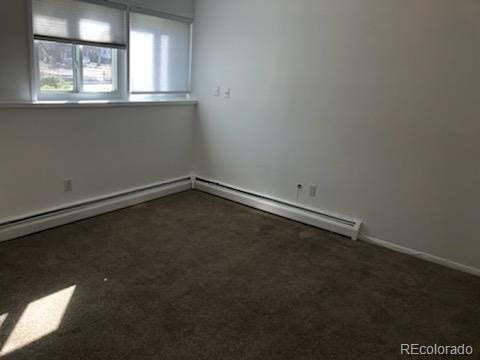 carpeted spare room featuring baseboard heating