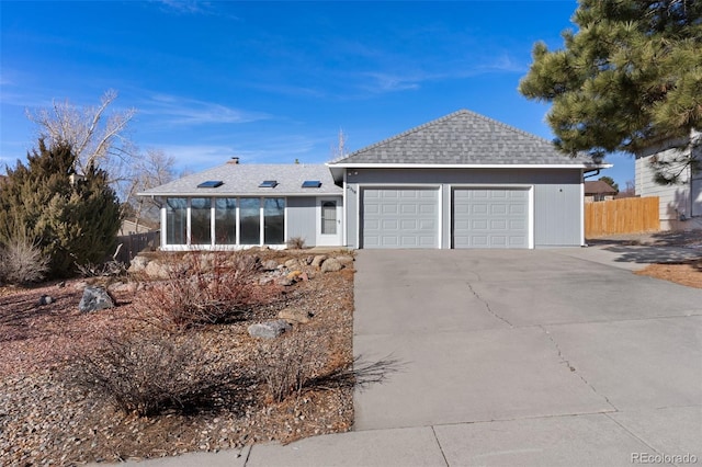 single story home featuring a sunroom, a shingled roof, fence, and concrete driveway