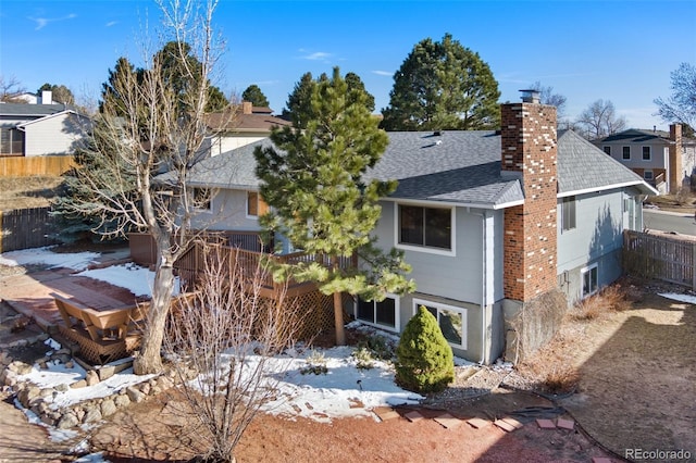 view of front of property featuring roof with shingles, fence, and a chimney