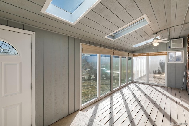 unfurnished sunroom featuring ceiling fan, lofted ceiling with skylight, wooden ceiling, and a wall mounted AC