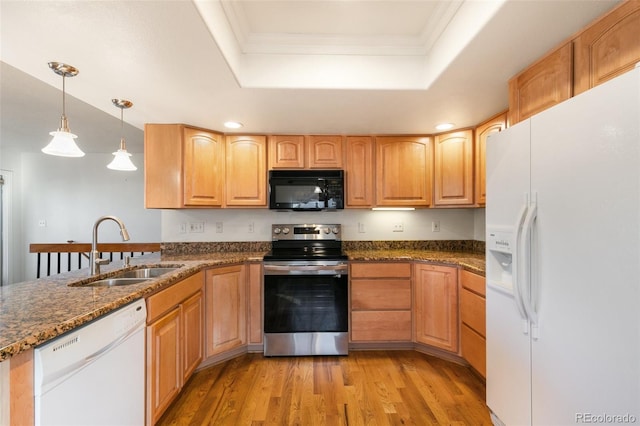 kitchen featuring white appliances, ornamental molding, a tray ceiling, light wood-type flooring, and a sink