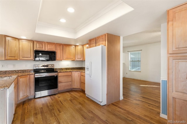 kitchen featuring white appliances, light wood finished floors, a raised ceiling, ornamental molding, and light brown cabinetry