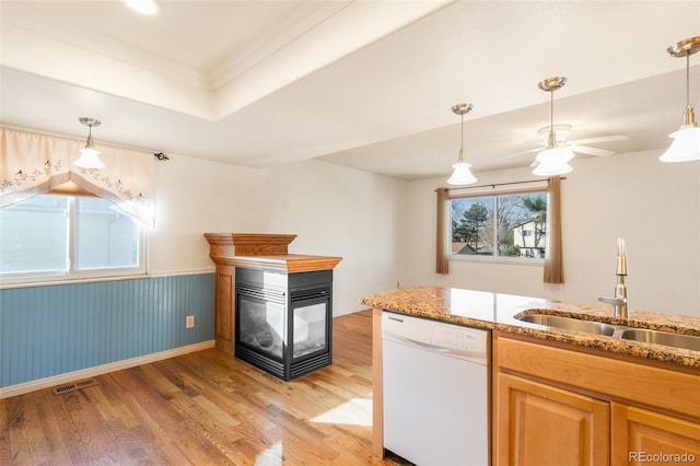 kitchen with white dishwasher, a multi sided fireplace, a sink, light stone countertops, and light wood finished floors