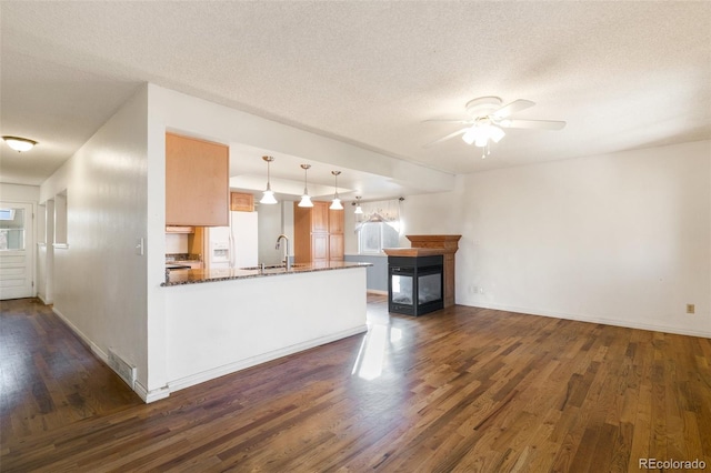 kitchen with visible vents, dark wood-style floors, white fridge with ice dispenser, a sink, and a multi sided fireplace