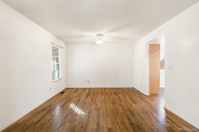 unfurnished room featuring a textured ceiling, wood finished floors, a ceiling fan, and baseboards