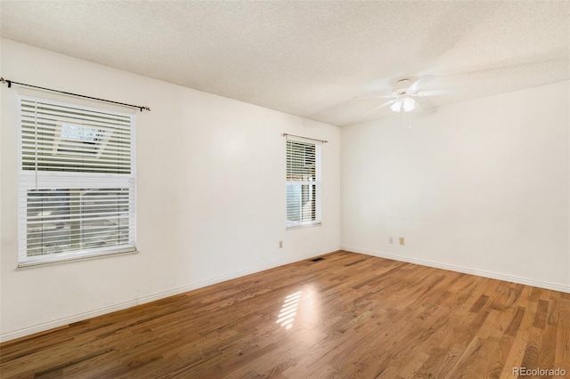 spare room with ceiling fan, a textured ceiling, baseboards, and wood finished floors