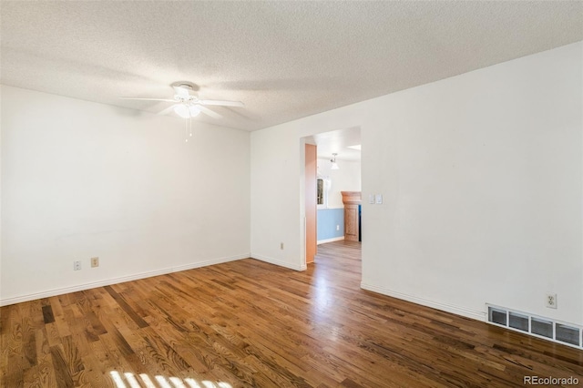 spare room featuring a textured ceiling, wood finished floors, visible vents, and baseboards