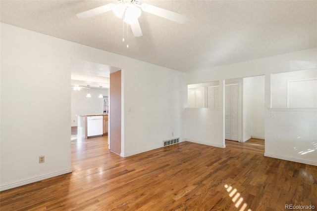 empty room featuring baseboards, a textured ceiling, visible vents, and wood finished floors