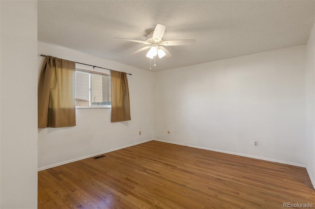 empty room featuring a ceiling fan, a textured ceiling, baseboards, and wood finished floors