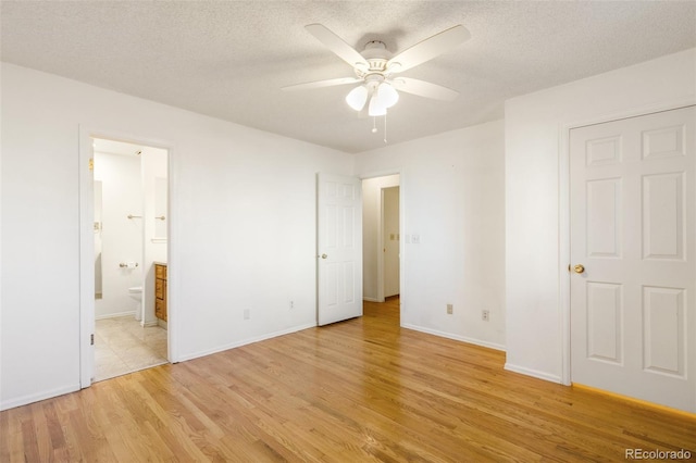 unfurnished bedroom with light wood-style floors, ensuite bath, baseboards, and a textured ceiling