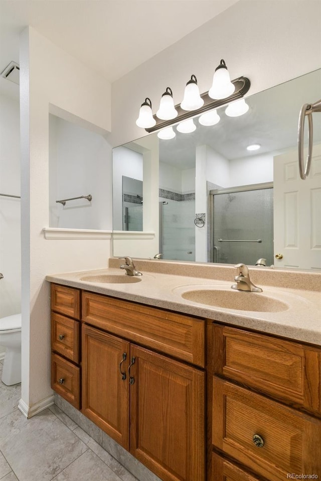 full bath featuring double vanity, a stall shower, a sink, and toilet