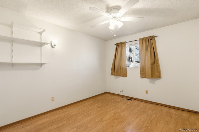 empty room with a textured ceiling, light wood finished floors, visible vents, and a ceiling fan