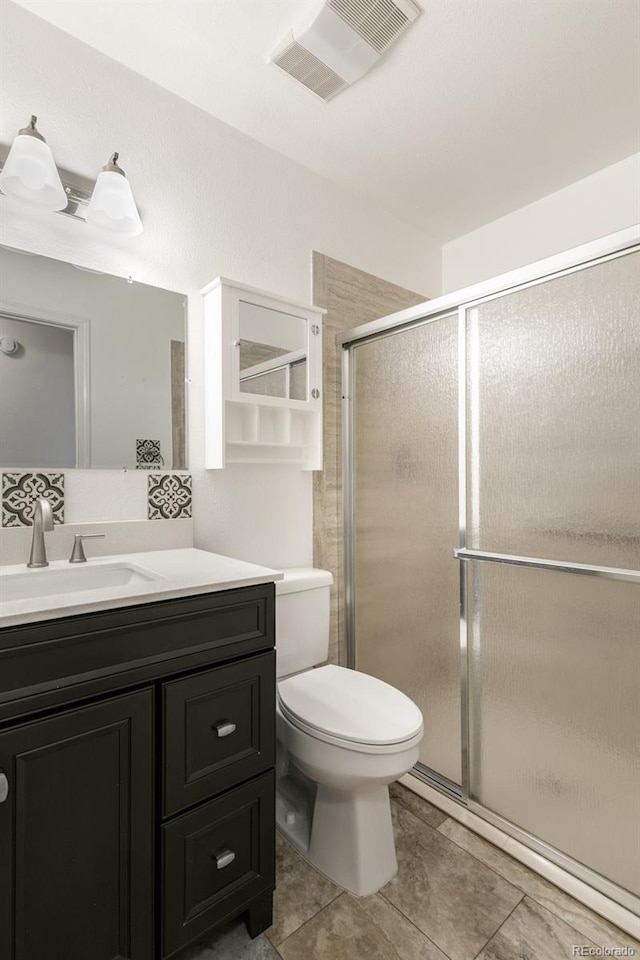 full bath with toilet, vanity, a shower stall, and visible vents