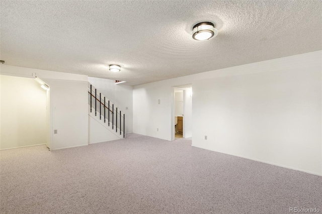 empty room featuring carpet flooring, a textured ceiling, and stairs