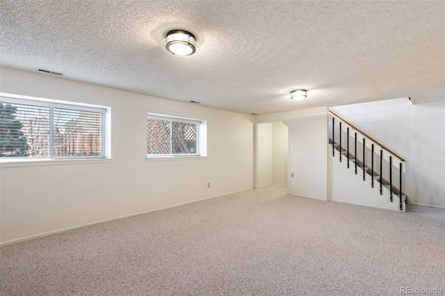 basement featuring a healthy amount of sunlight, stairs, visible vents, and carpet flooring