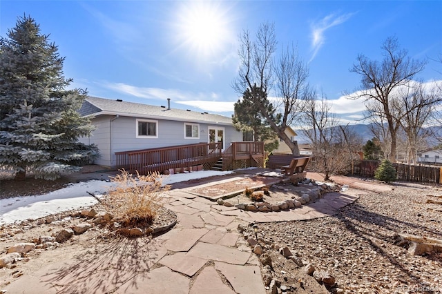 rear view of property featuring fence, a wooden deck, and a patio