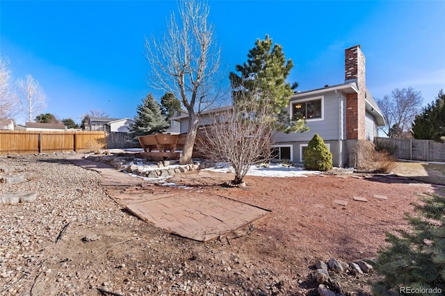 rear view of house with a chimney and fence