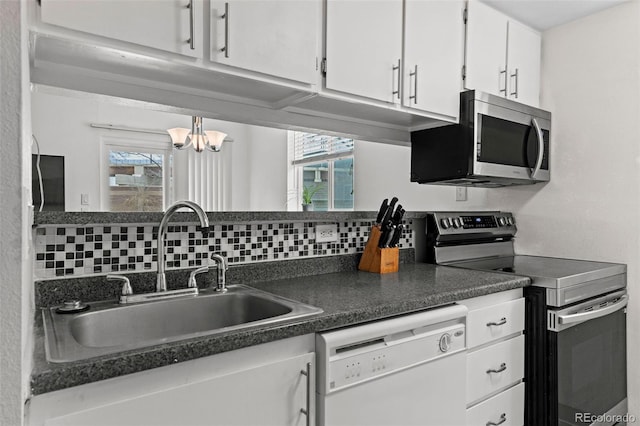 3021 S Ursula Cir Unit 102, Aurora, CO 80014 - kitchen with appliances with stainless steel finishes, a sink, white cabinetry, dark countertops, and healthy amount of natural light