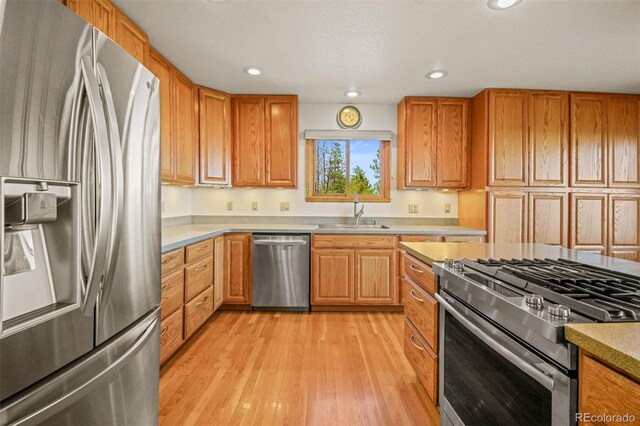 kitchen with sink, stainless steel appliances, and light hardwood / wood-style flooring