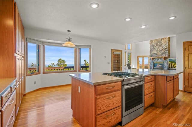 kitchen featuring stainless steel range with gas cooktop, a kitchen island, pendant lighting, and light hardwood / wood-style floors