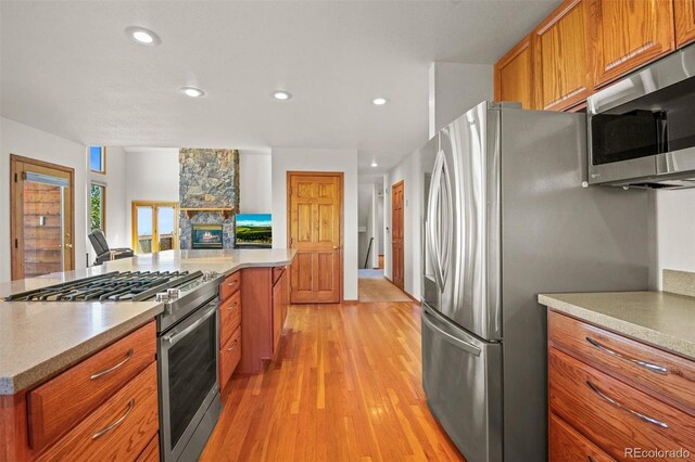 kitchen featuring a fireplace, light wood-type flooring, and appliances with stainless steel finishes