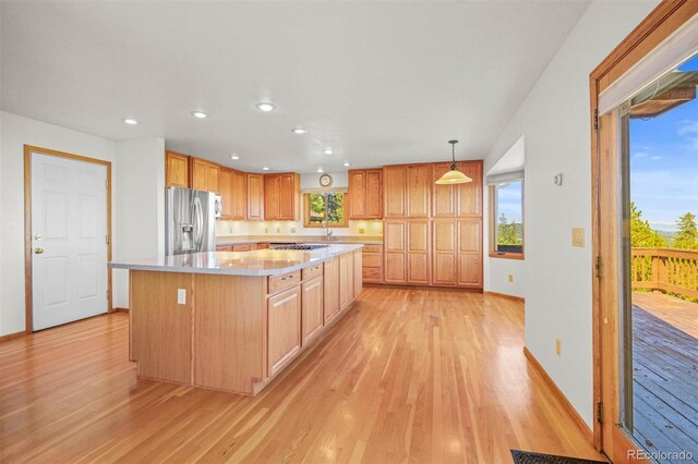 kitchen with stainless steel appliances, a healthy amount of sunlight, light hardwood / wood-style flooring, pendant lighting, and a kitchen island