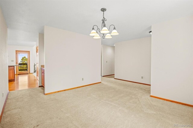 carpeted spare room with a notable chandelier