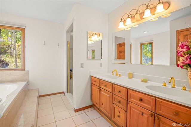 bathroom with tile patterned flooring, vanity, a relaxing tiled tub, and a wealth of natural light