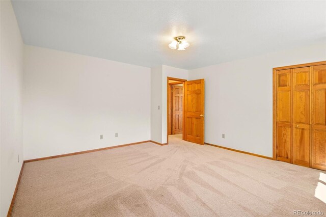 unfurnished bedroom featuring light colored carpet and a closet