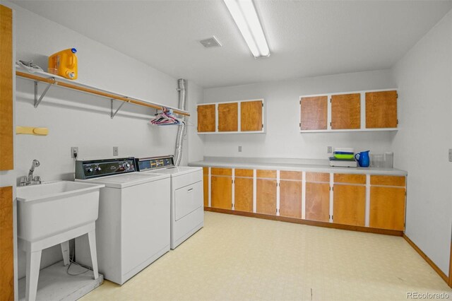 clothes washing area featuring washing machine and dryer and cabinets