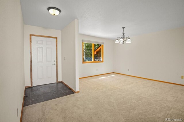 entryway featuring dark colored carpet and an inviting chandelier