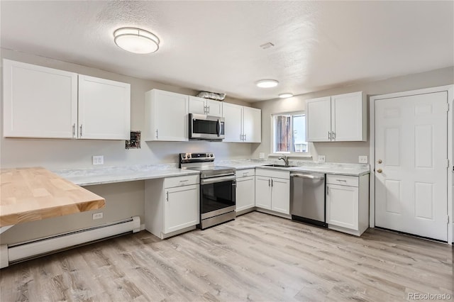 kitchen with stainless steel appliances, baseboard heating, white cabinetry, sink, and light wood-type flooring