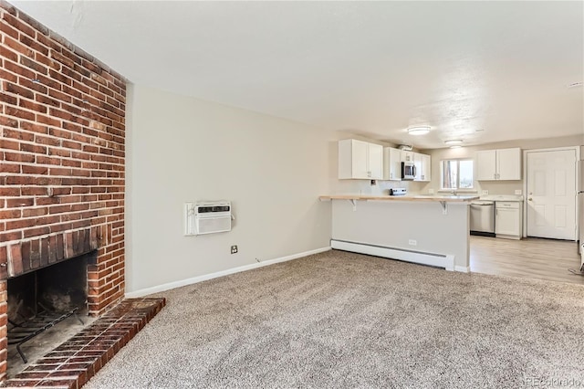 unfurnished living room featuring a wall mounted air conditioner, a baseboard radiator, light wood-type flooring, a fireplace, and brick wall