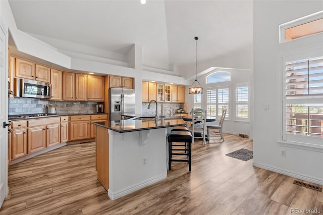 9576 E 147th Pl, Brighton, CO 80602 - kitchen with stainless steel appliances, a kitchen breakfast bar, dark countertops, light wood-type flooring, and a high ceiling