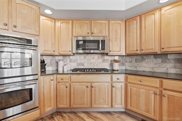 9576 E 147th Pl, Brighton, CO 80602 - kitchen featuring appliances with stainless steel finishes, light brown cabinetry, dark countertops, tasteful backsplash, and light wood-type flooring