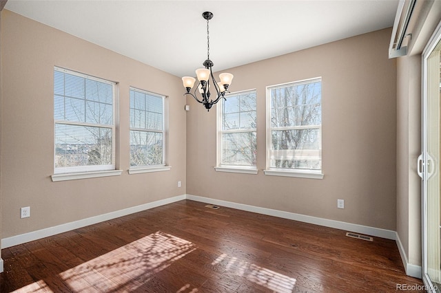 unfurnished dining area featuring dark hardwood / wood-style floors and an inviting chandelier