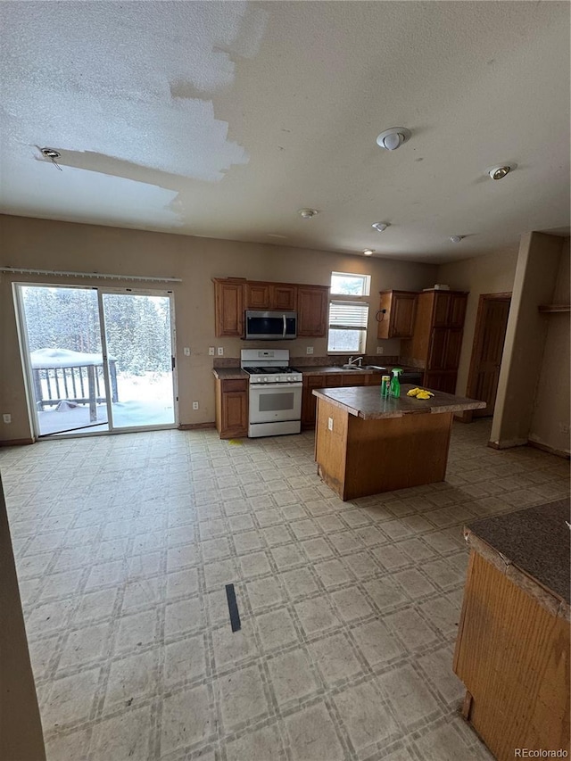 kitchen featuring a textured ceiling, a kitchen island, gas range gas stove, and sink