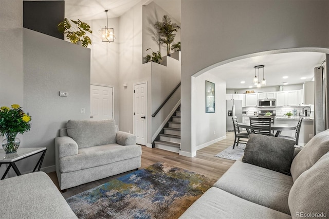 living room featuring a notable chandelier, wood-type flooring, and a high ceiling