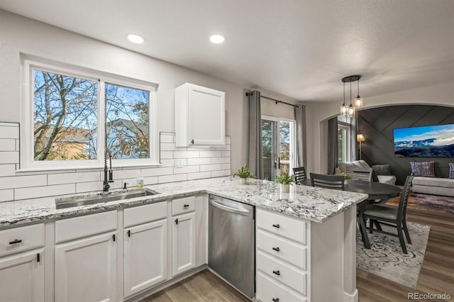 kitchen featuring sink, white cabinetry, decorative light fixtures, stainless steel dishwasher, and kitchen peninsula