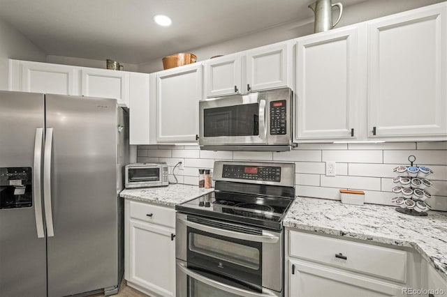 kitchen featuring appliances with stainless steel finishes, white cabinets, and decorative backsplash