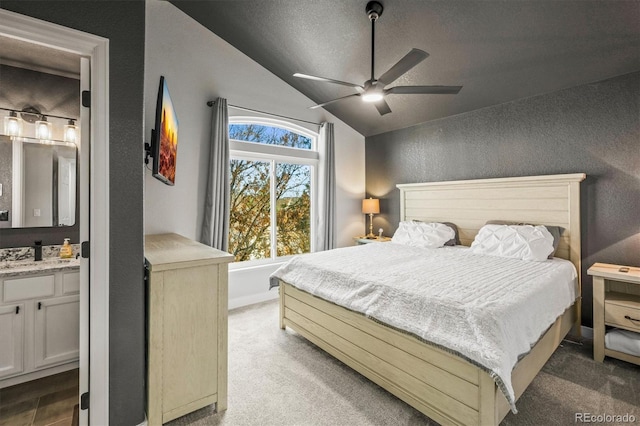 carpeted bedroom featuring ceiling fan, connected bathroom, vaulted ceiling, and a textured ceiling