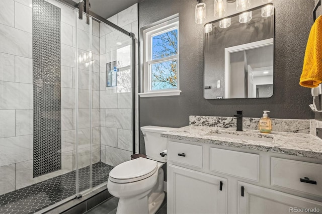 bathroom featuring vanity, a shower with shower door, and toilet