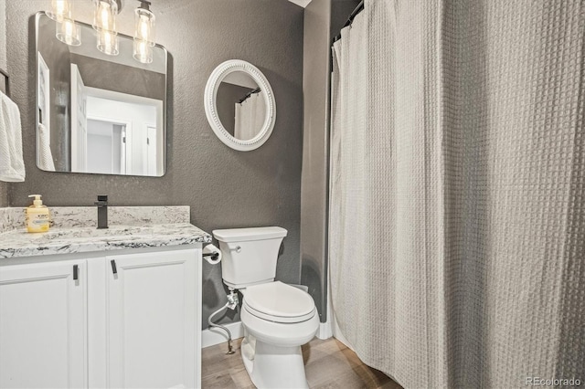 bathroom with vanity, hardwood / wood-style floors, walk in shower, and toilet